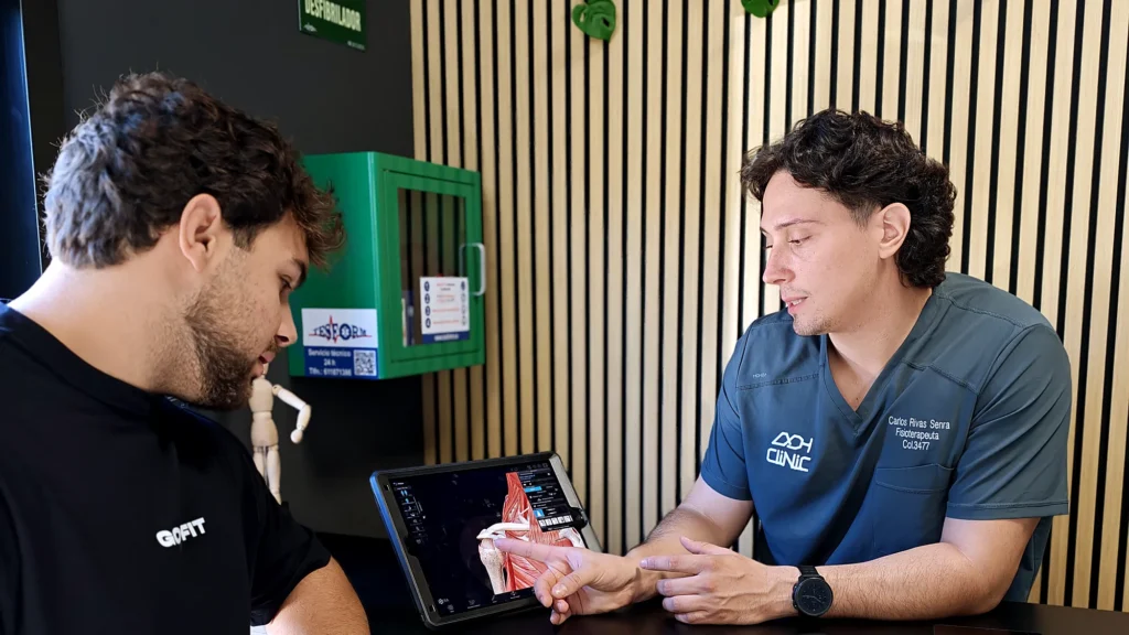 Fisioterapeuta de ADH Clinic explicando el plan de readaptación a un paciente